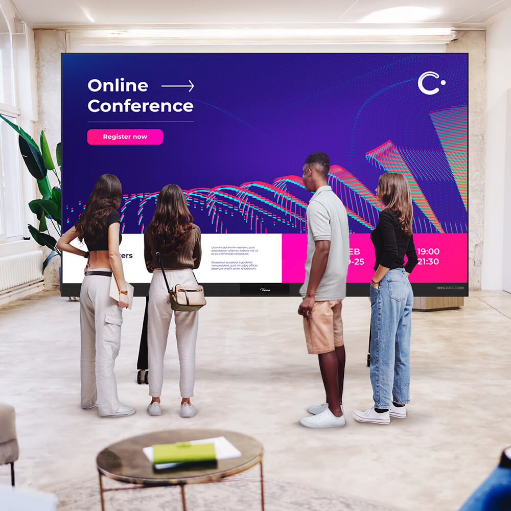 Group of young professionals viewing an interactive digital display promoting an online conference with event details and registration information